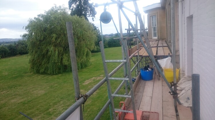 Scaffolding standing against a large three-storey building.